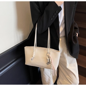 Detail of minimalist cream bucket bag with braided rope handle and tassel charm