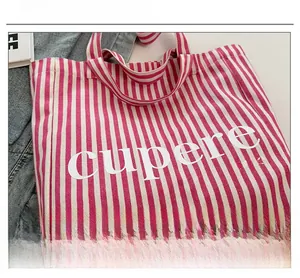 Detail of red and white striped canvas tote bag with artistic Cupere Dune lettering