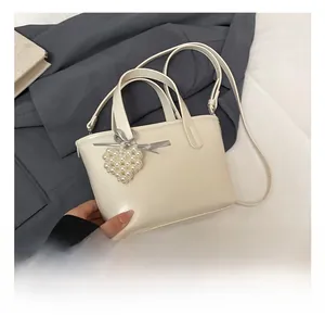 Detail of cream white bucket bag with pearl heart charm and silver bow accent