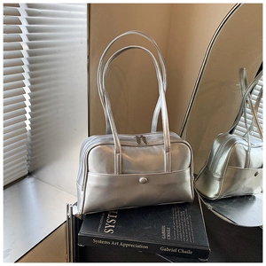 Detail view of silver metallic Boston bag on art books with minimalist aesthetic lighting