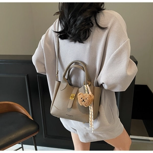 Litchi pattern leather bucket bag with gold hardware and striped scarf shown on model