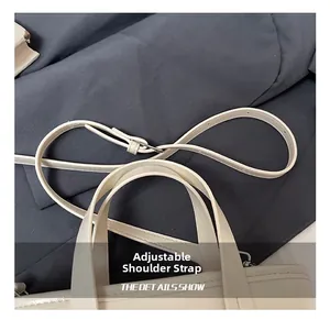 Detail view of cream bucket bag showing adjustable shoulder strap and reinforced stitching