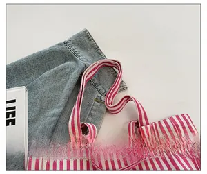 Close-up of wide striped shoulder strap on a pink and white canvas tote bag