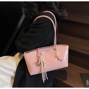 Close-up of pink patent leather bucket bag with embossed logo and woven rope charm