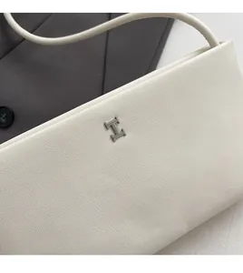 Primo piano della borsa in pelle martellata avorio con fibbia metallica a forma di H