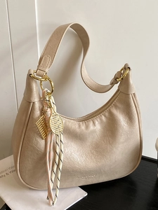Chic beige oil wax leather hobo bag with gold tennis racket charm and shoulder strap