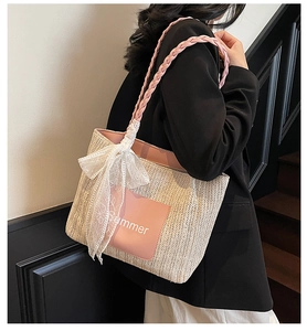 Detail of woven straw tote bag with pink straps, lace bow, and Summer text embroidery