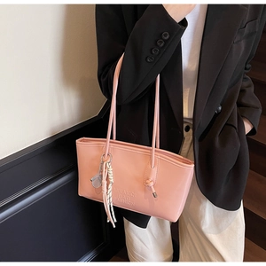 Pink PU leather tote bag detail with tennis racket pendant and woven tassel accessory