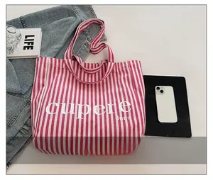 Detailed top view of pink striped canvas tote bag with magazine and denim jacket