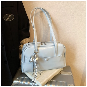 Detail of light blue Boston bag with silver bow charm and dual zipper on a suitcase
