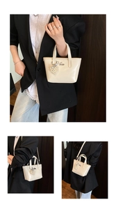 Detail view of cream white glossy tote bag with pearl heart charm and shoulder strap