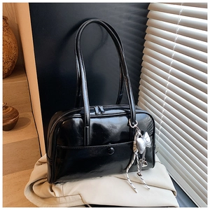 Detail of black glossy Boston bag with silver bow charm and elegant button front pocket