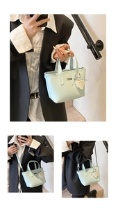 Detail view of a light blue bucket bag with silver logo plate and heart pearl charm