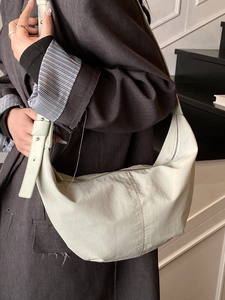 Minimalist white crescent shoulder hobo bag worn by a model in a simple indoor setting