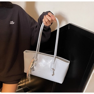 Detail of grey patent leather bucket bag with silver glossy finish and thin straps