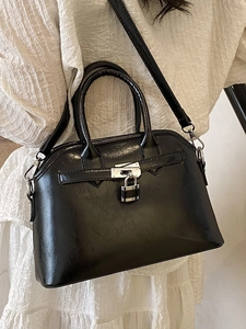 Elegant black shell-shaped handbag in glossy leather finish with silver buckle decoration