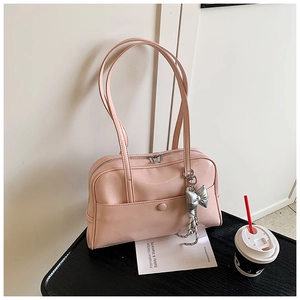 Detail of pink patent leather Boston bag with silver bow charm and snap front pocket