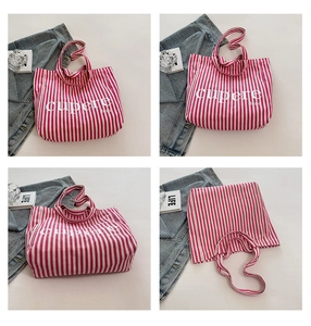 Detail view of large capacity canvas tote bag with pink vertical stripes and art text