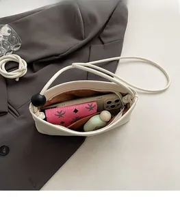 Interno della borsa a spalla in pelle color crema con spazio per cellulare e piccoli cosmetici