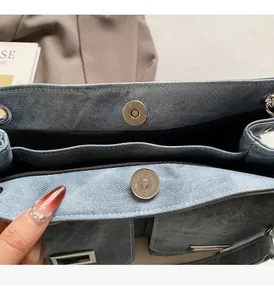 Détail d'un sac cabas en denim bleu clair avec boucle magnétique argentée et compartiments