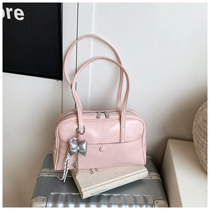 Detail of light pink oil-wax leather Boston bag with double handles and a bow charm