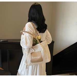 Detail of hand-woven straw tote with leather Summer patch and white lace scarf decor