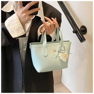 Detail of light blue mini tote bag with pearl heart charm and metallic silver logo plate