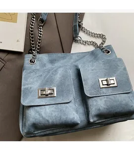 Détail du sac cabas en jean délavé avec deux poches avant et fermoirs rotatifs argentés