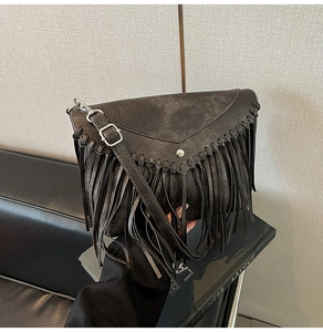 Close-up of black leather crossbody bag featuring fringe tassels and triangle flap cover