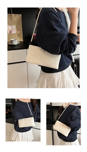 Dettaglio di una borsa a tracolla minimalista bianco crema con fibbia in metallo H argento