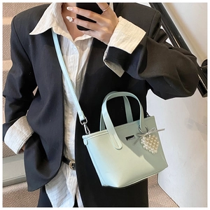 Detail of light blue bucket bag with heart-shaped pearl pendant and silver bow charm
