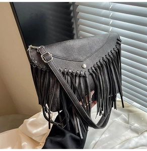 Makrodetail der schwarzen Vintage-Umschlagtasche mit langen Boho-Fransen und Silberschnalle