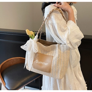 Detail of beige woven tote bag with brown leather patch and white Summer lettering design