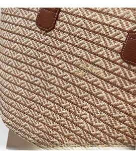 Detail of woven straw bag showing fine fiber texture and leather strap with white stitching
