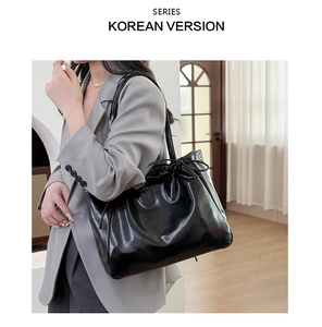 Detail of glossy black soft leather tote bag showing pleated texture and drawstring closure