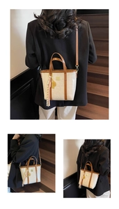 Close-up of cream embossed tote with brown handles and a stylish tassel ornament