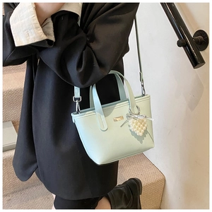 Close-up of light blue crossbody bag with a heart pearl charm on a street style model