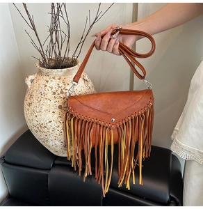 Close-up of brown fringe crossbody bag with woven details and bohemian tassel accents