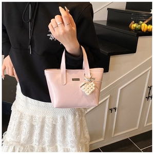 Detail view of pink PU leather handbag with heart-shaped pearl charm and metallic logo plate