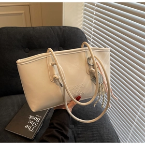 Detailed view of cream PU leather bucket bag with embossed lettering and tennis racket charm