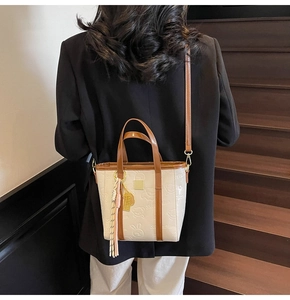 Fashionable cream tote bag with embossed cartoon patterns worn by model on stairs