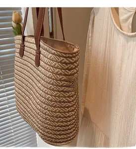 Detail of straw woven tote bag featuring brown leather straps and secure zipper closure