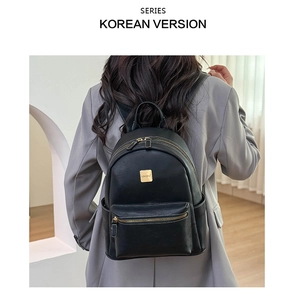 Detail of minimalist black leather backpack with gold zipper and MKBV logo plaque