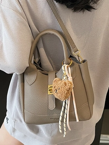 Grey lychee grain leather bucket bag with top handle and teddy bear charm crossbody strap