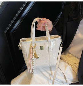 Detail of cream leather bucket bag with embossed rabbit patterns and decorative tassels