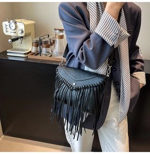 Detail of a black leather tassel envelope bag featuring a V-shaped flap and silver hardware