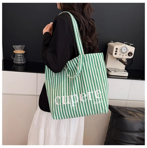 Close-up of green and white striped canvas tote bag with artistic cupere dune text