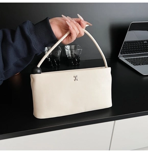 Dettaglio della borsa in pelle bianco crema con logo H in metallo e perla nera decorativa