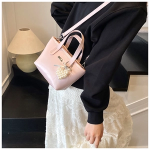 Detail of pink PU leather bucket bag with heart pearl charm and slim shoulder strap
