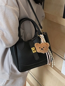Chic black lychee grain leather bucket bag with a plush bear charm and silk scarf